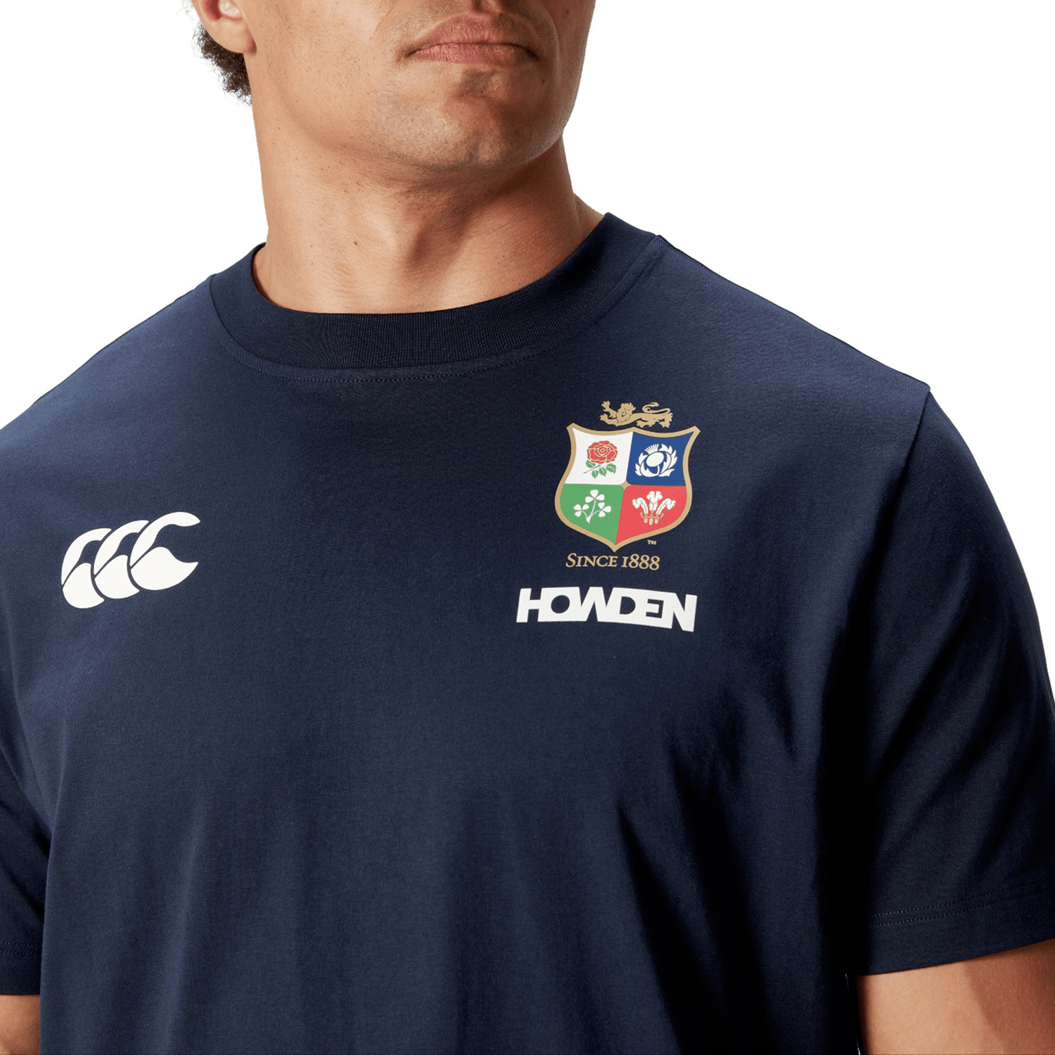 A British & Irish Lions supporter proudly wears the Canterbury 2025 Cotton Jersey Tee in navy blue, showcasing a sports logo and "SINCE 1888" text on the front, crafted from soft organic cotton.