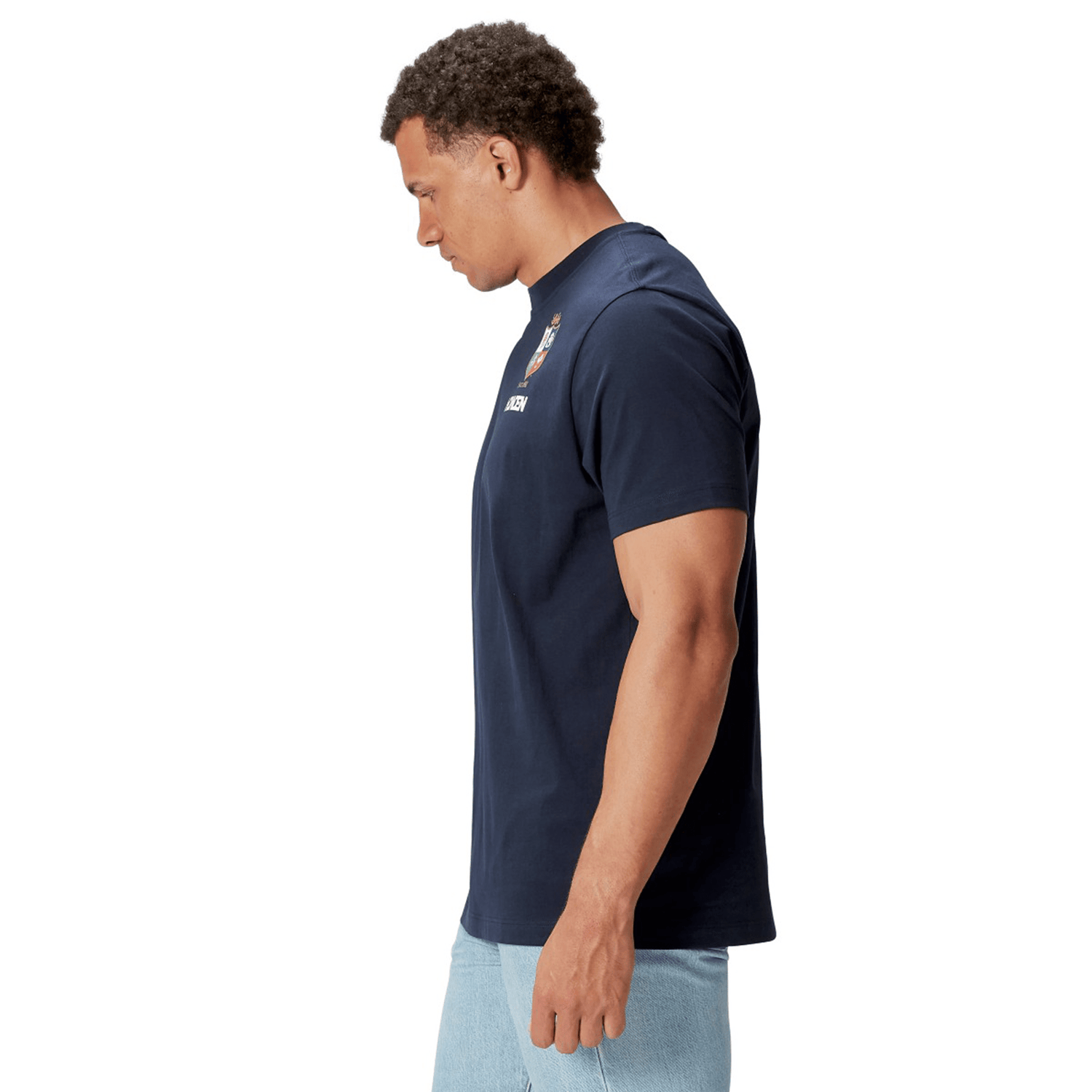 A model wearing the British & Irish Lions 2025 Cotton Jersey Tee by Canterbury and light blue jeans, crafted from organic cotton, stands in profile against a white background.