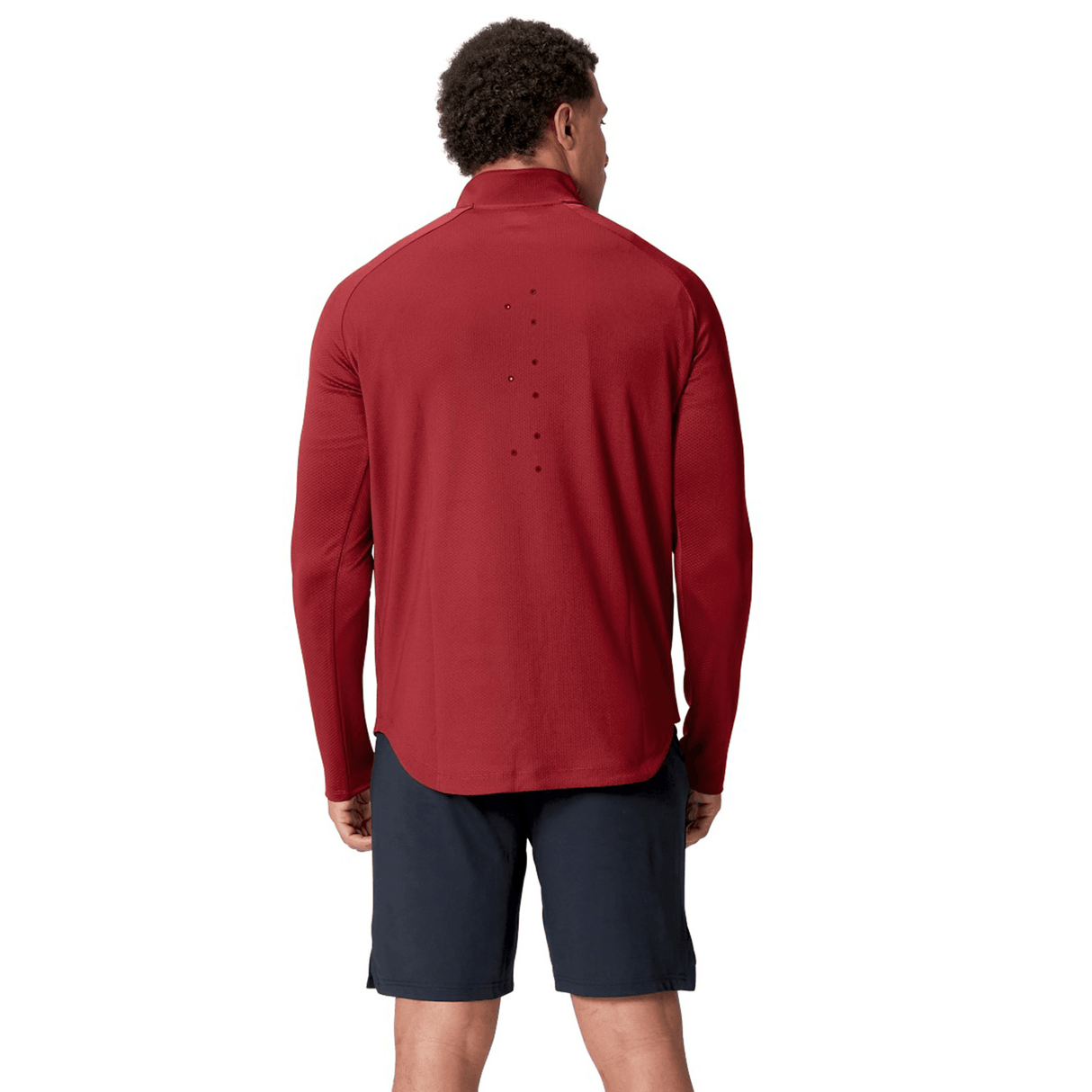 A person wearing a red British & Irish Lions 25 Everest First Layer Top by Canterbury and black shorts stands with their back to the camera.