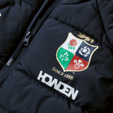 Close-up of a black British & Irish Lions 2025 Microlight Gilet by Canterbury, crafted from recycled polyester. It showcases a colorful embroidered crest with floral motifs and the text "Since 1888," with the word "HOWDEN" printed below the crest.