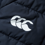 Close-up of the British & Irish Lions 2025 Microlight Gilet by Canterbury, featuring a dark fabric with a white logo of three overlapping stylized wave shapes, made from recycled polyester.