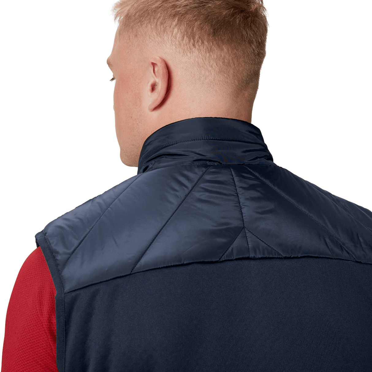 A person with short blonde hair is seen from behind wearing the British & Irish Lions 2025 Microlight Gilet by Canterbury, crafted from recycled polyester in navy and black, over a red shirt.