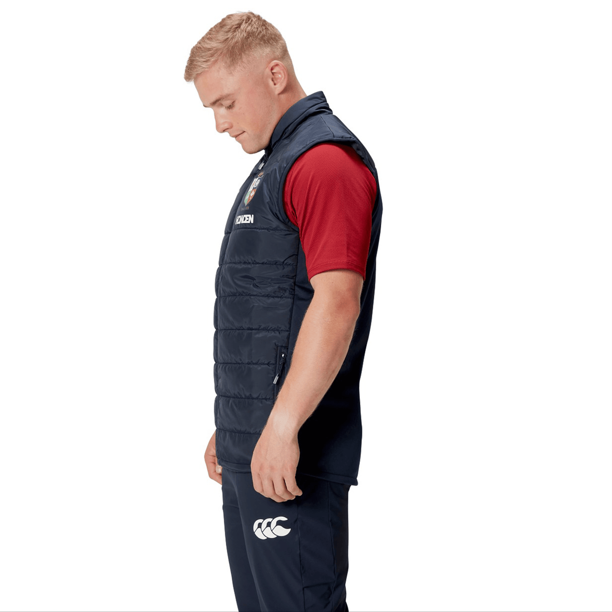A man wearing the British & Irish Lions 2025 Microlight Gilet by Canterbury, crafted from thermoreg fabric, stands in profile against a white background.