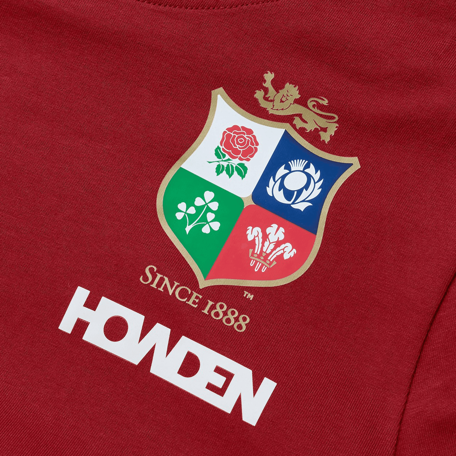 Introducing the Women's British & Irish Lions 25 Cotton Jersey Tee by Canterbury, a red shirt made from organic cotton. It features a vibrant multi-colored sports emblem adorned with symbols of a rose, thistle, shamrock, and dragon. Perfect for rugby enthusiasts, this tee proudly displays the text "SINCE 1888" and "HOWDEN," reflecting the spirit of the British & Irish Lions.