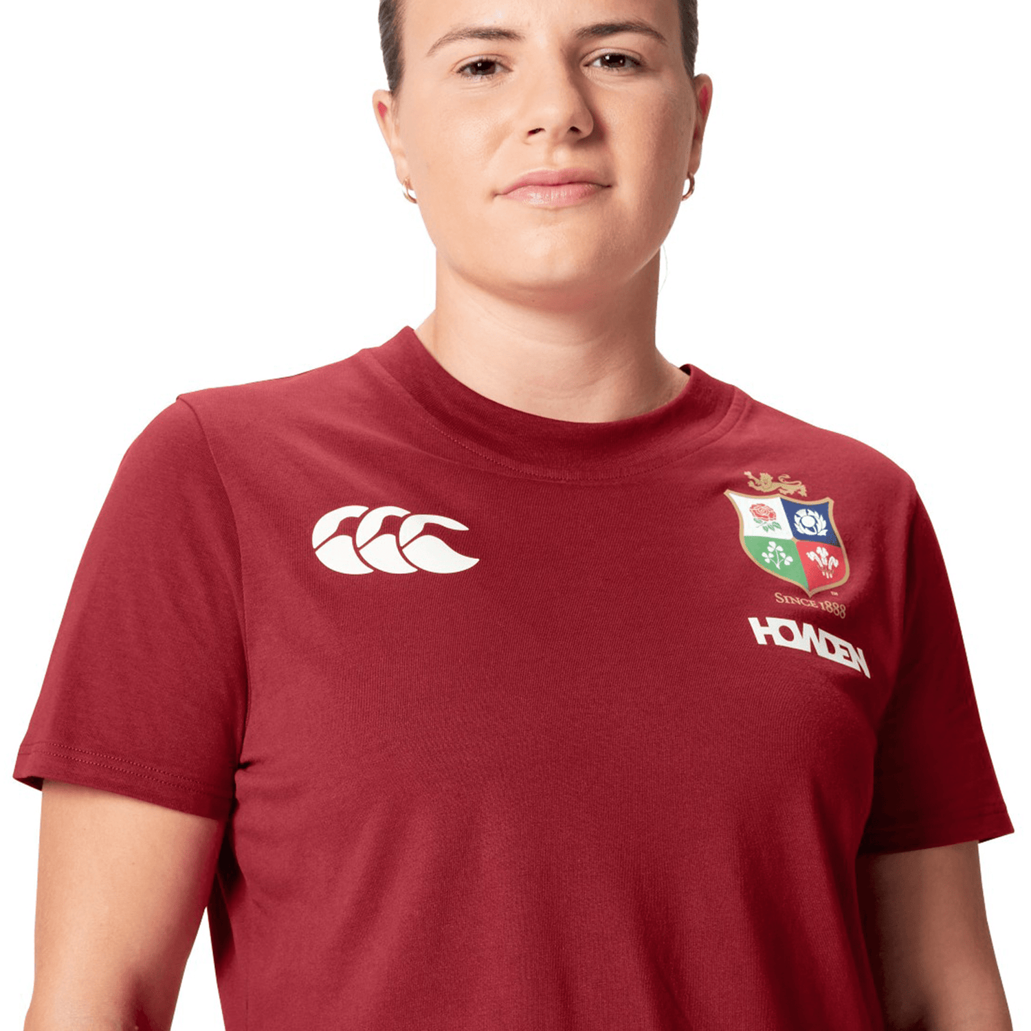 A rugby supporter proudly wears a Women's British & Irish Lions 25 Cotton Jersey Tee by Canterbury, featuring logos on the front, embodying the spirit of the British & Irish Lions.