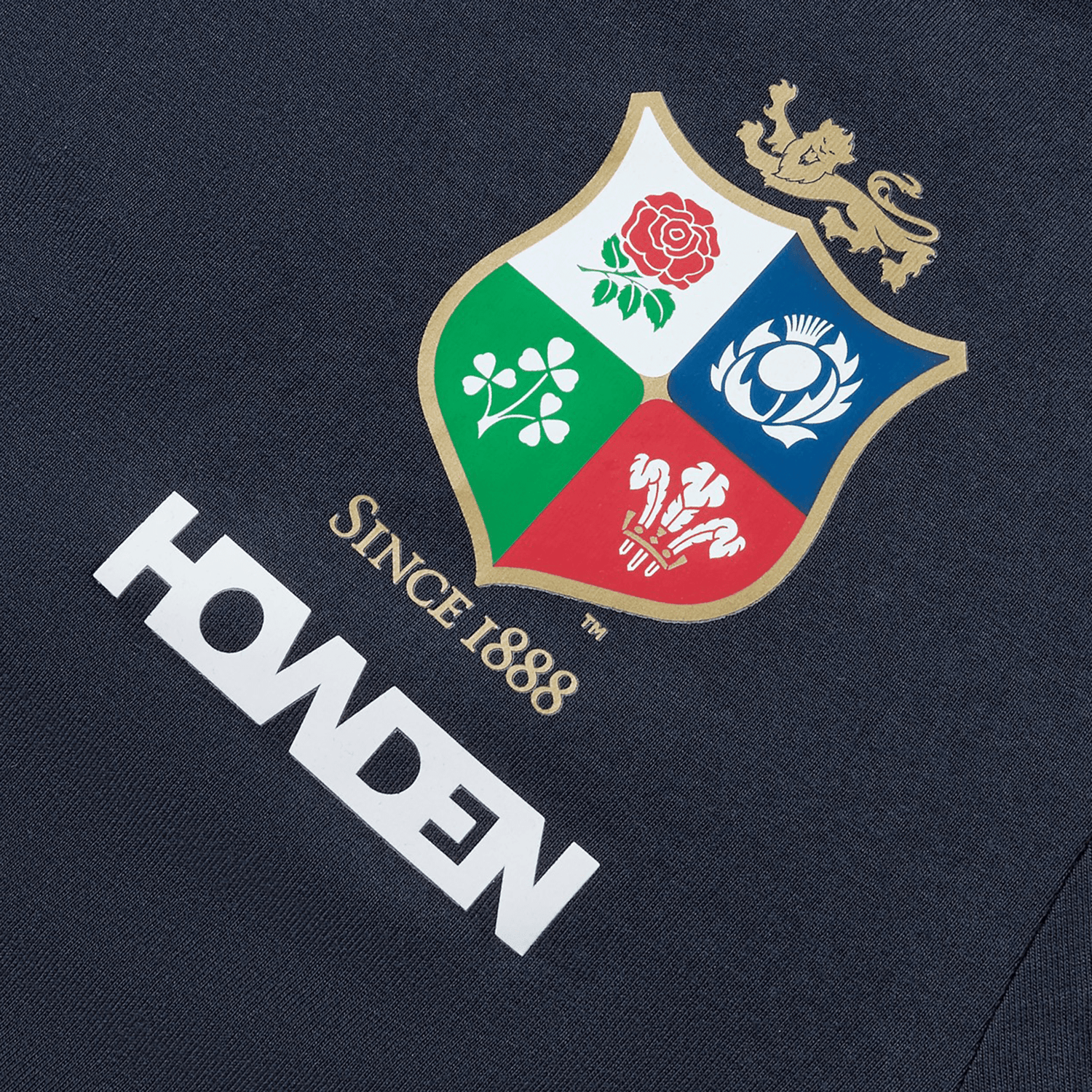 Close-up of a logo featuring a shield with a lion and four emblems: a rose, thistle, shamrock, and leek; the text reads "SINCE 1888" and "HONDEN" below. The British & Irish Lions 2025 Women's Cotton Jersey Tee by Canterbury is perfect for the rugby supporter in your life.