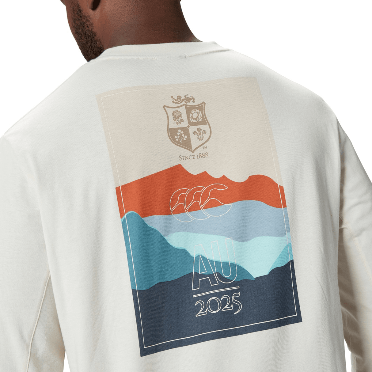 A person wearing a beige sweatshirt that resembles the British & Irish Lions 25 Outback Long Sleeve Tee by Canterbury, adorned with a vibrant graphic on the back featuring abstract shapes and the text "AU 2025," perfectly captures the adventurous essence of Canterbury designs.