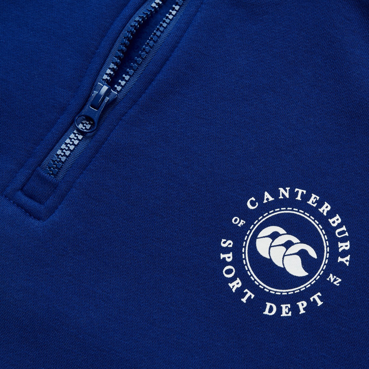 Close-up of a blue Canterbury Sport Dept 1/4 Zip Pullover featuring a circular logo with three kiwis and "Canterbury Sport Dept N.Z." It boasts rib-knit cuffs for comfort, making it perfect for athletic or casual wear.