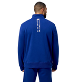 Individual wearing a blue Canterbury Sport Dept 1/4 Zip Pullover, facing away, with "Canterbury" and logo on the back, and rib-knit cuffs.