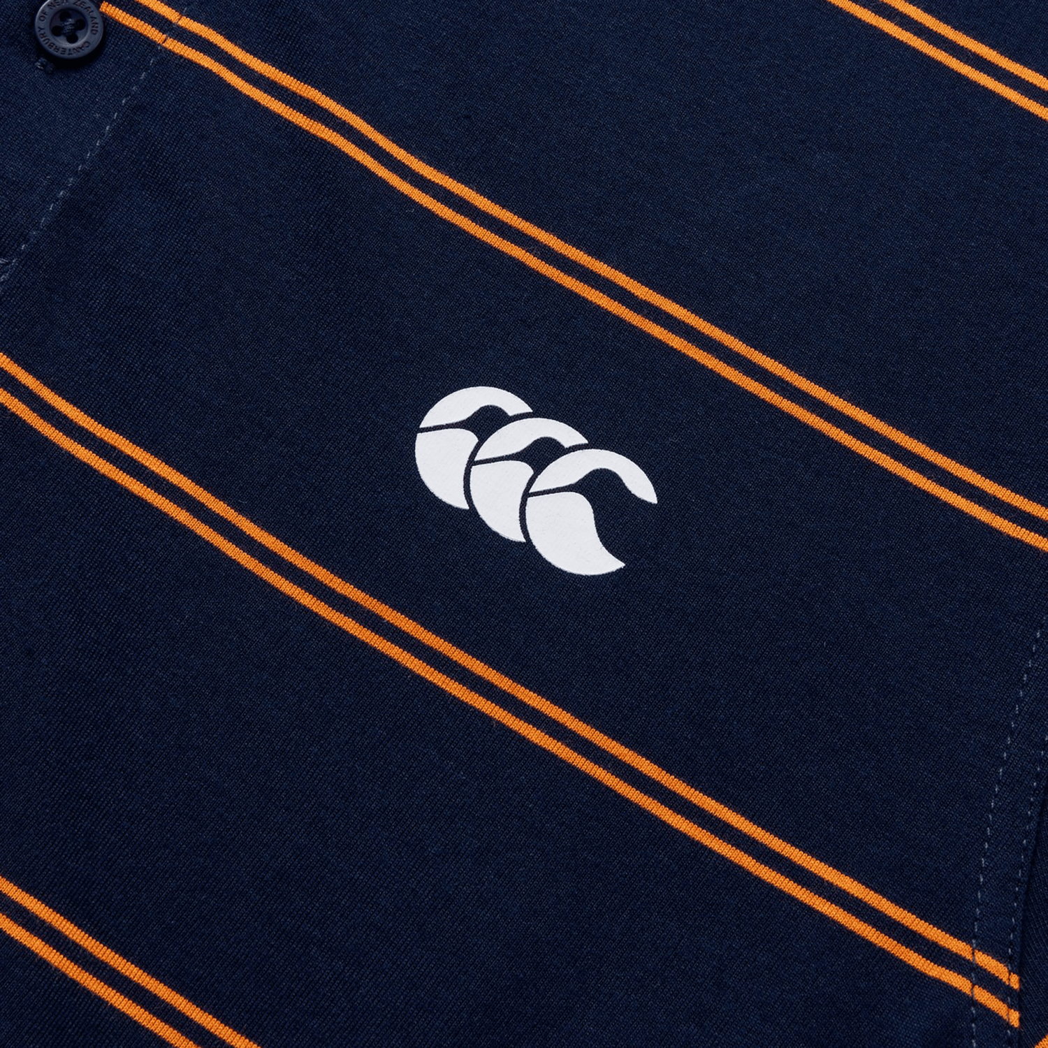 Close-up of the Canterbury Fundamental Yarn-Dye Stripe Polo in dark blue with orange stripes and a white logo featuring three overlapping shapes.