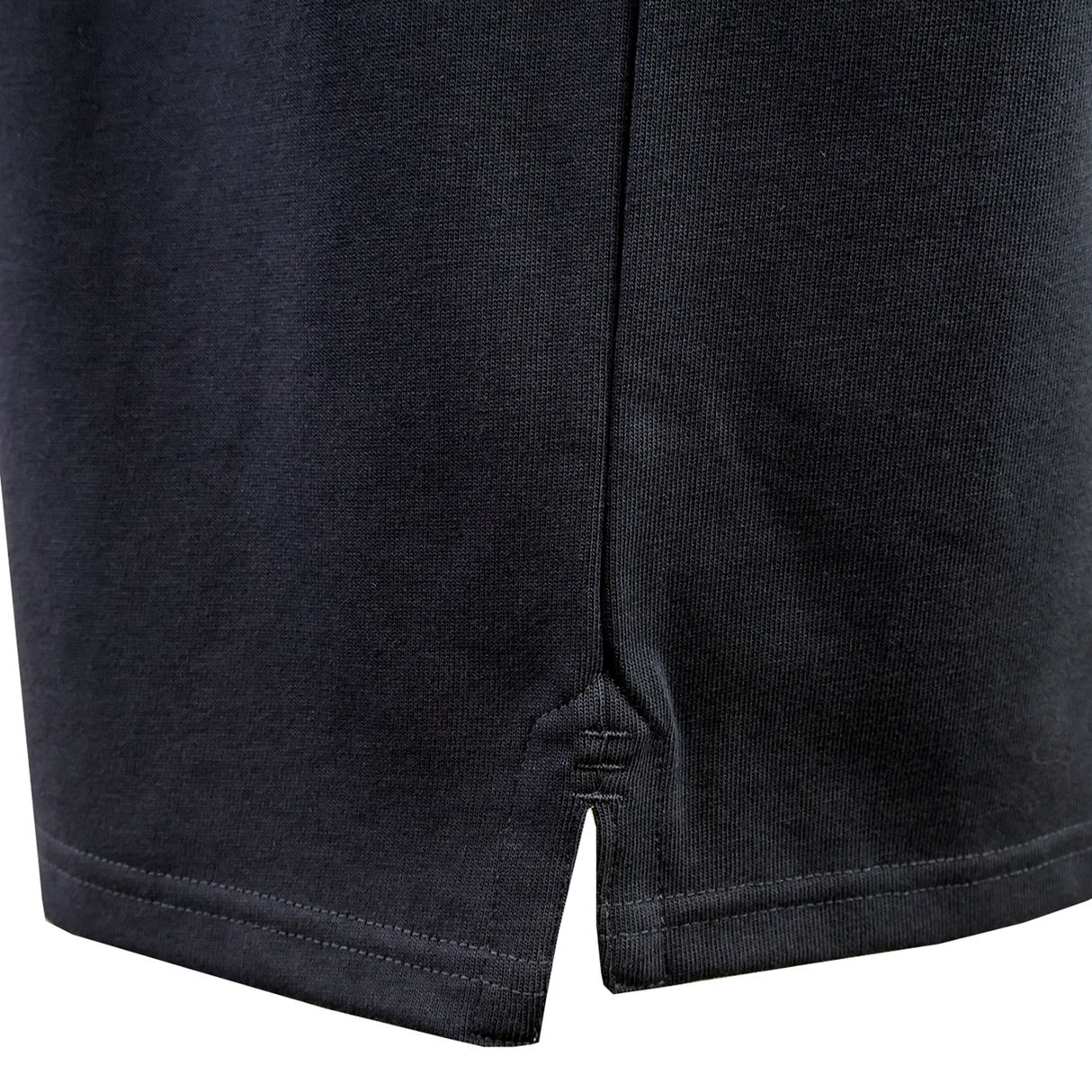 Close-up of the hemline on the Canterbury Fundamental Solid Dye Short Sleeve Rugby Jersey by Canterbury, showing a black finish with a small side slit and visible stitching details.