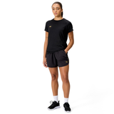 A person faces forward wearing a black t-shirt, Canterbury Women's Tempo+ 5" Training Shorts in black, white socks, and black sneakers against a plain white background.