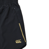 Close-up of Canterbury Women's Tempo+ 5" Training Shorts in black, featuring a yellow logo and side stripe, elastic waistband, zippered pocket, and moisture-wicking fabric for comfort.