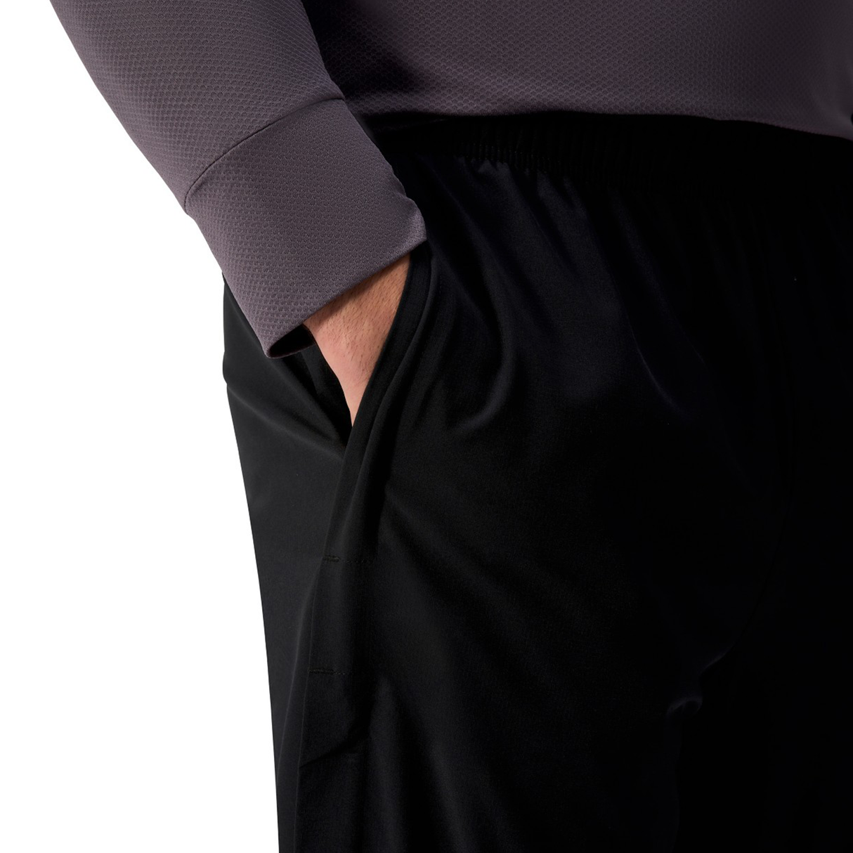 A person wearing a gray long-sleeve top and black Canterbury Tempo+ 32" Trackpant stands with their right hand in their pants pocket.