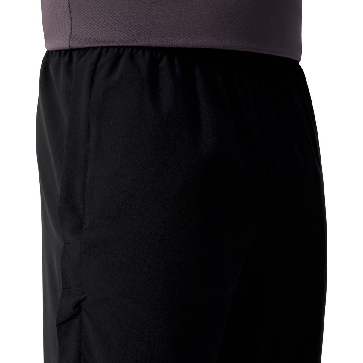 Close-up of a person wearing the Canterbury Tempo+ 32" Trackpant and a dark purple or gray textured shirt, showing only the waist and upper thigh area.