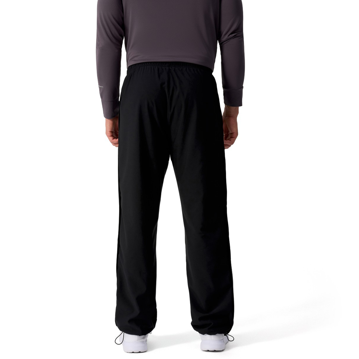 Someone wearing a long-sleeve dark shirt and Canterbury Tempo+ 32" Trackpant stands with their back to the camera against a white background.