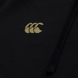 A close-up of the gold Canterbury "CCC" logo on black fabric, with a black drawstring—highlighting the refined details of the Tempo+ Hoodie by Canterbury.