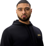 A man with a short beard wears the Canterbury Tempo+ Hoodie, featuring a gold logo on the chest, and stands against a white background facing the camera.