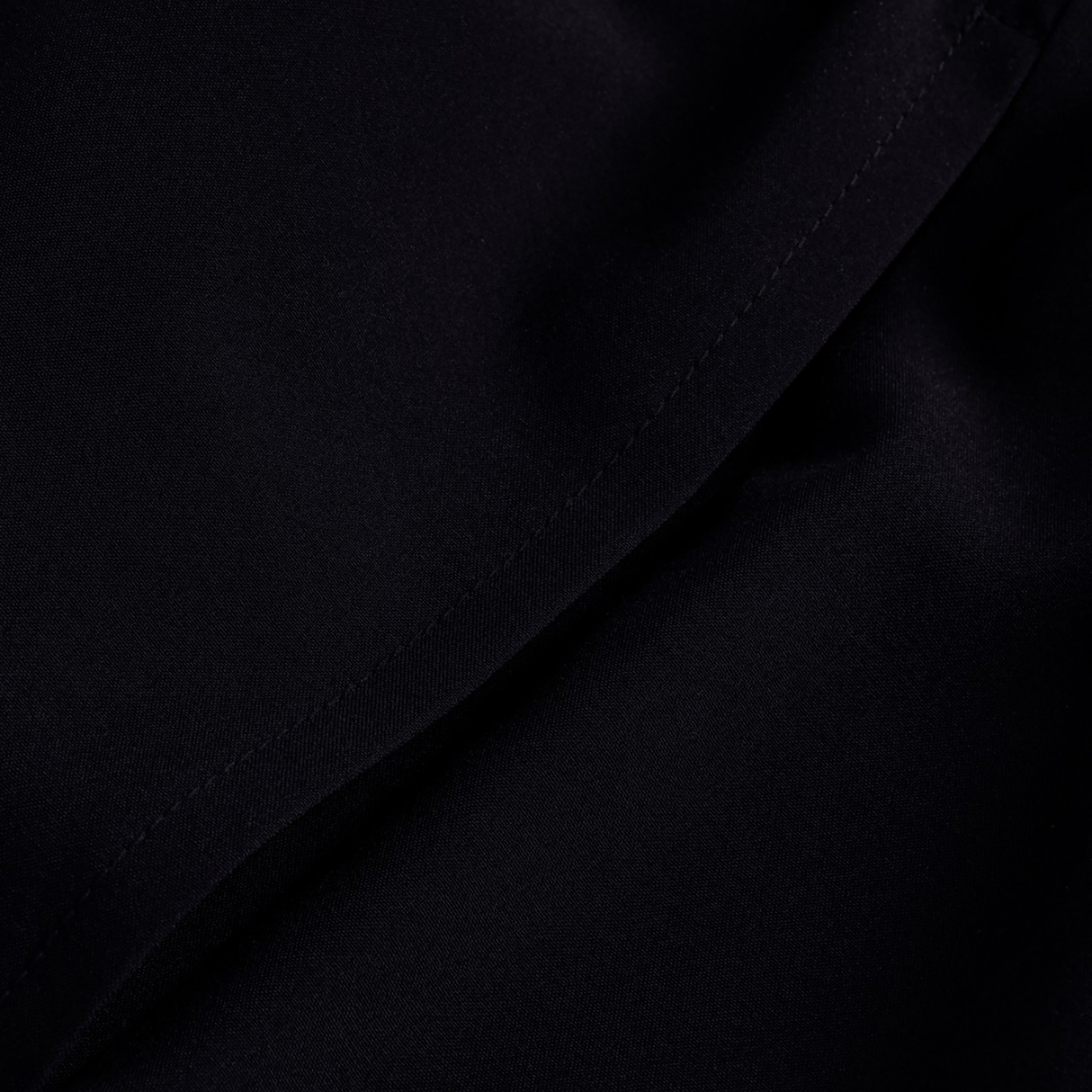 Close-up of the black fabric on the Canterbury Tempo+ 5" 2-In-1 Short, highlighting a diagonal seam running from the bottom left to the top right.