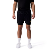 A man wearing a black t-shirt, Canterbury Tempo+ 5" 2-In-1 Shorts, white crew socks, and white sneakers stands against a plain white background.