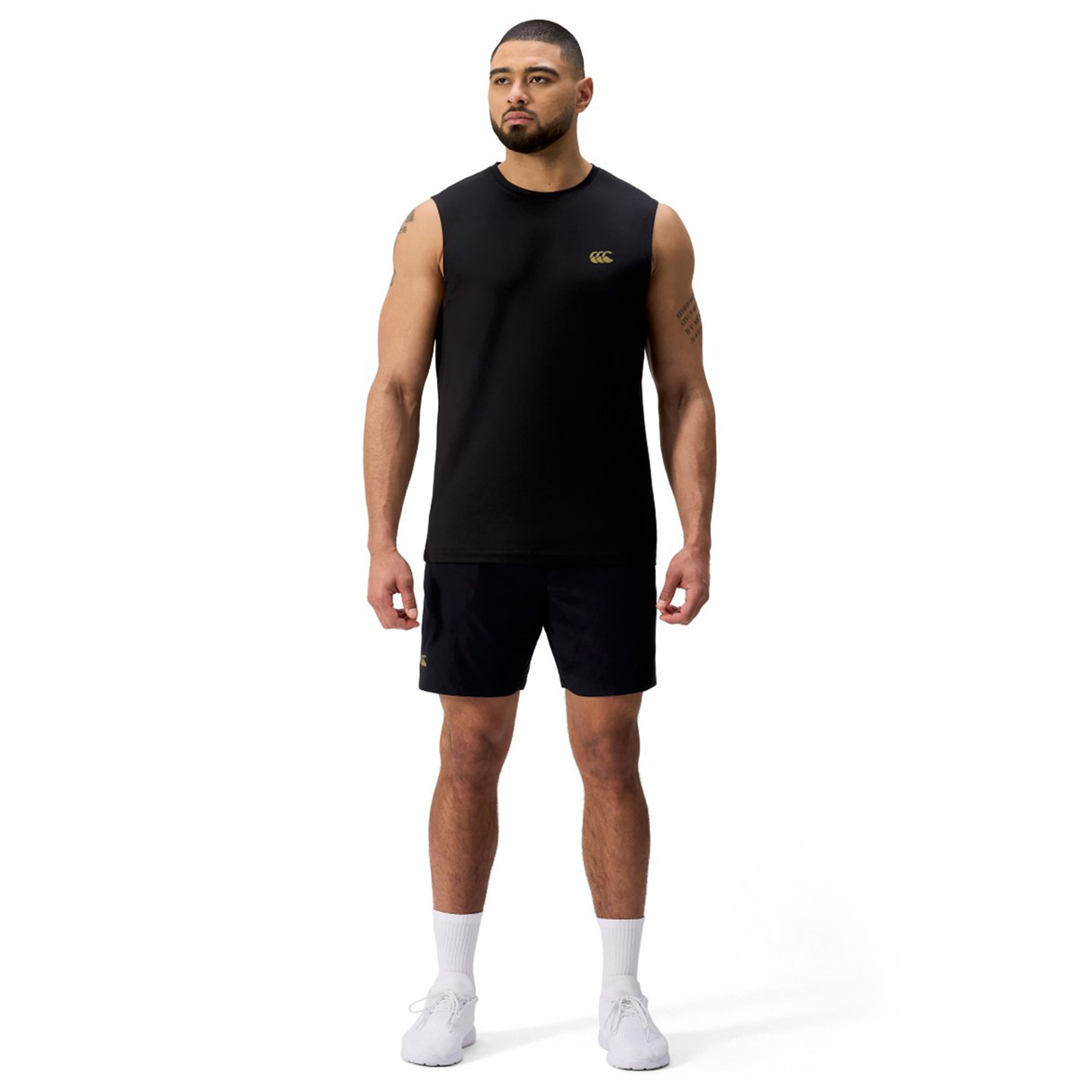 A man faces forward wearing the Canterbury Tempo+ Training Tank, black shorts, white socks, and white athletic shoes against a plain white background.