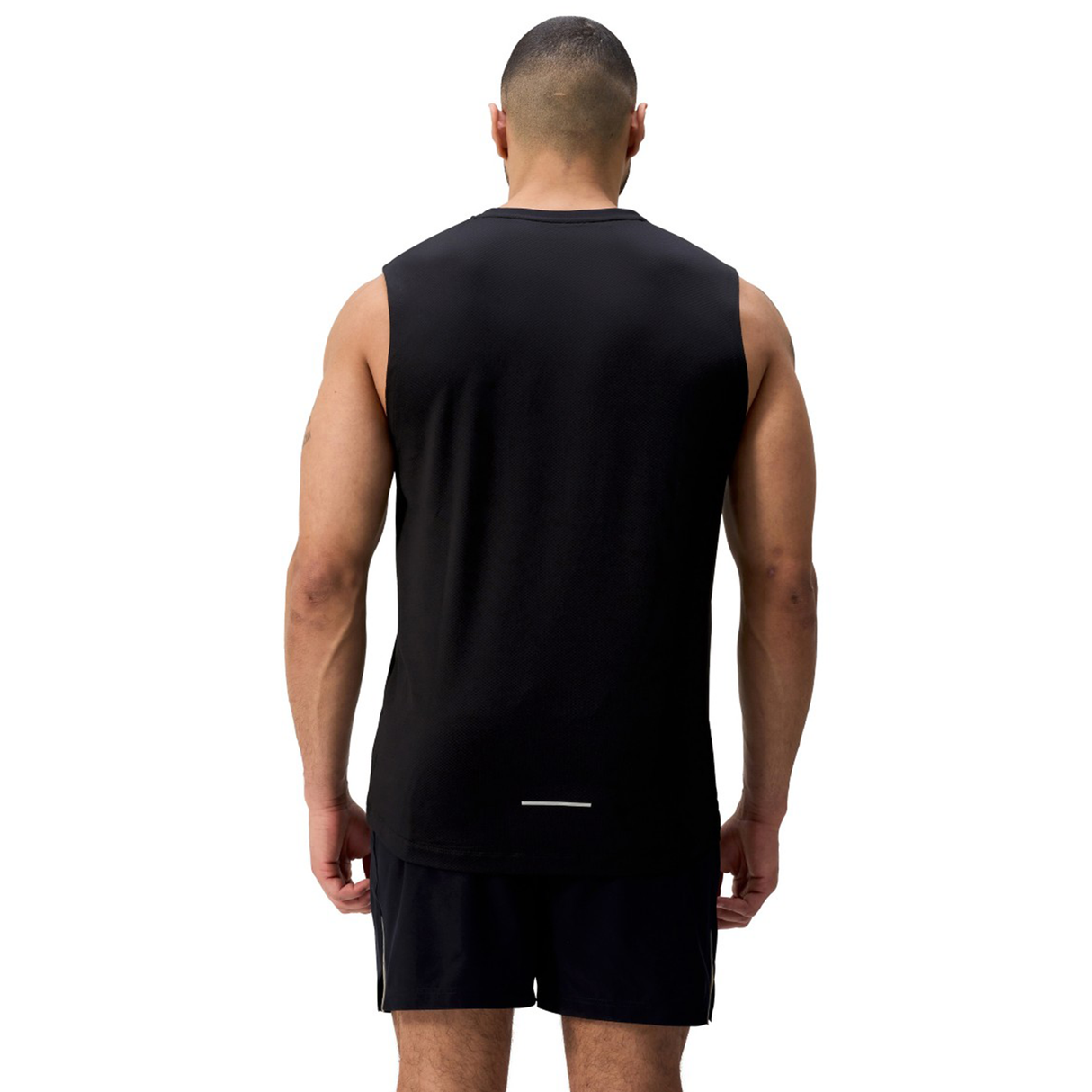 A man stands with his back to the camera against a white background, wearing the Canterbury Tempo+ Training Tank in black and matching athletic-fit black shorts.