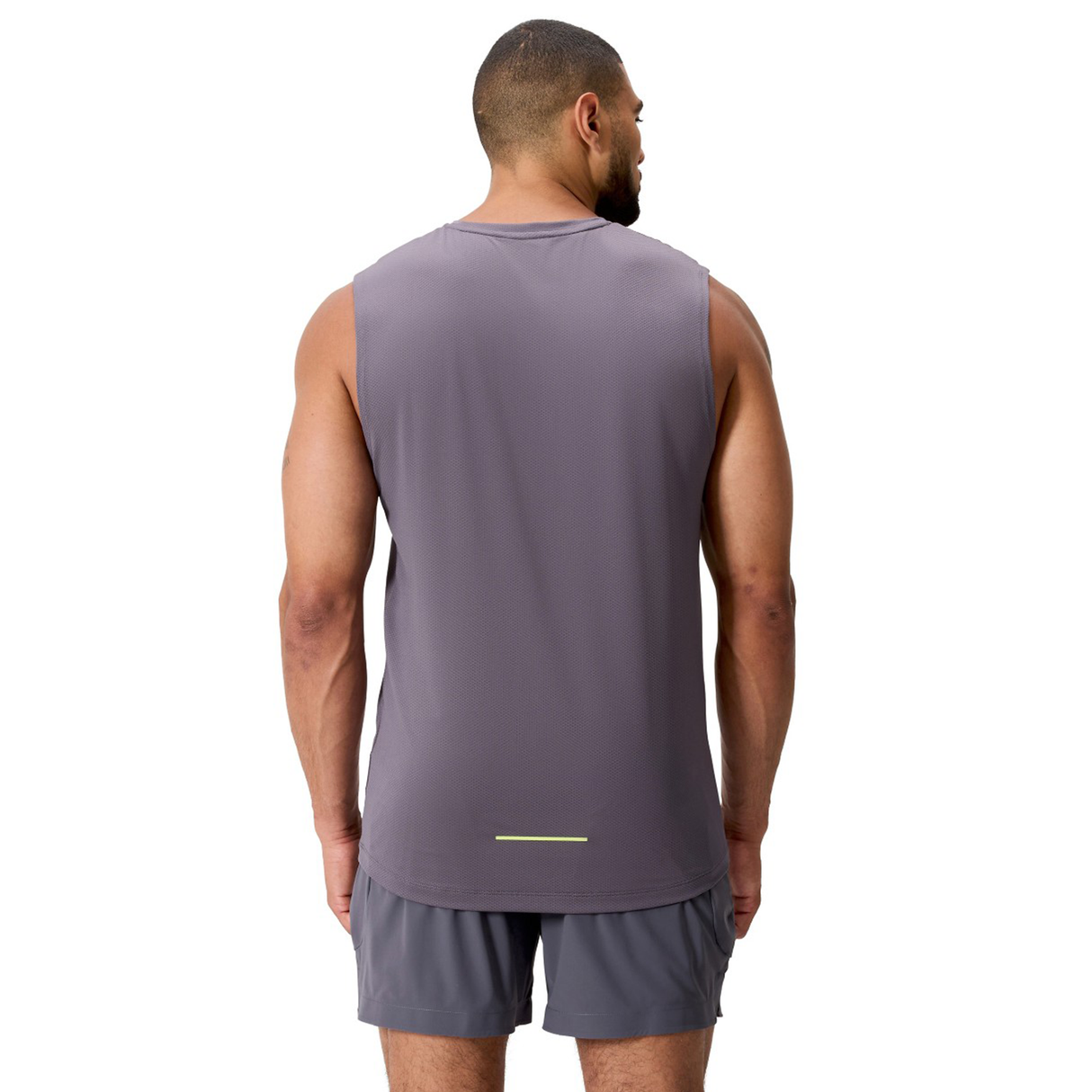 A man stands with his back to the camera, wearing a Canterbury Tempo+ Training Tank and matching shorts in gray, against a white background.