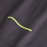 Close-up of textured dark gray fabric from the Canterbury Tempo+ Training Tank, featuring a single yellow wavy line and moisture-wicking properties.