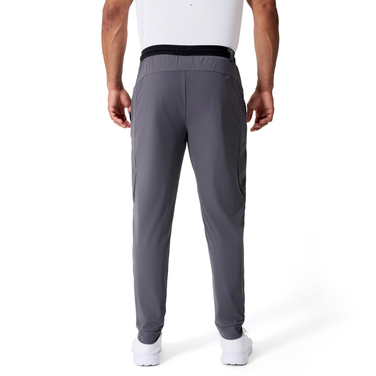 A person is shown from the back wearing Canterbury Everest Woven Pants in gray with white shoes, standing against a plain white background.