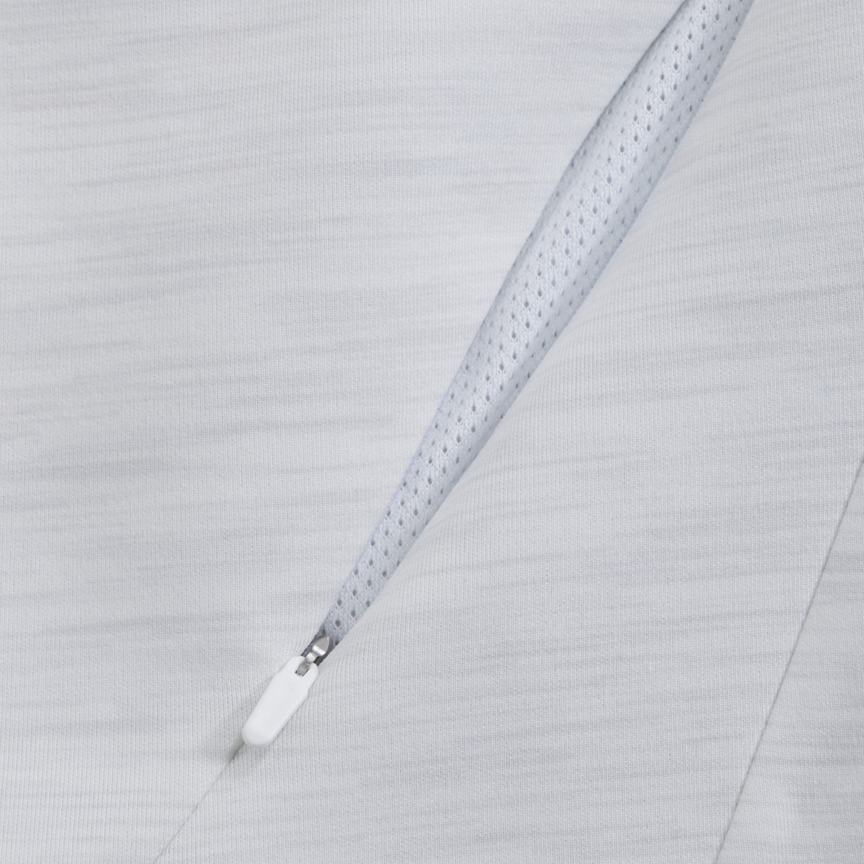 Close-up of the Everest Training Full-Zip Hoodie by Canterbury in light gray, showing the textured inner lining and a diagonal zippered pocket with a white zipper pull.