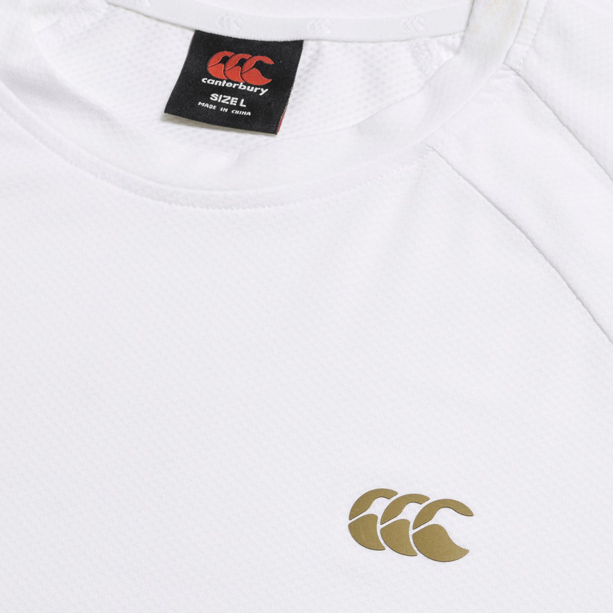 A detailed view of the Everest Training Tee by Canterbury, highlighting the gold Canterbury logo on the chest and black size label at the collar. This tee offers a performance fit for both comfort and style.
