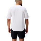 A man faces away against a plain white background, wearing the Everest Training Tee by Canterbury in loose white with back ventilation holes, paired with black shorts.