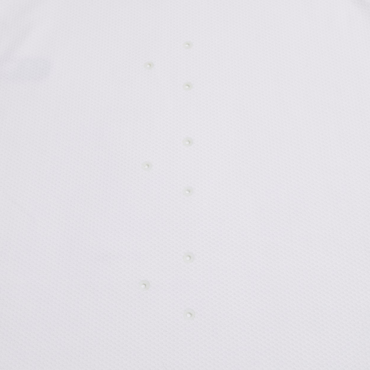 The Everest Training Tee by Canterbury features a plain white textured surface with two vertical rows of evenly spaced round bumps, inspired by the performance fit of a rugby training shirt.