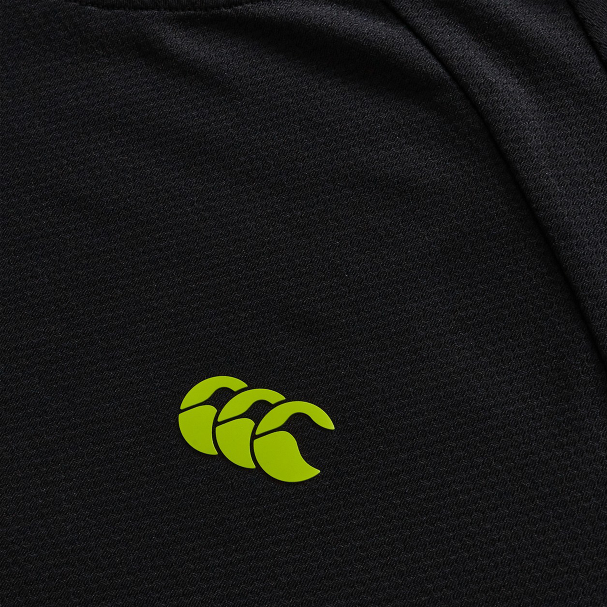 Close-up of the black textured fabric on the Everest Training Tee by Canterbury, featuring a yellow-green sportswear logo—a performance-fit tee designed for rugby players.