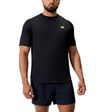 A man wears the black Everest Training Tee by Canterbury, featuring a small yellow logo and matching black shorts. Designed for rugby players seeking a performance fit, he stands against a white background.