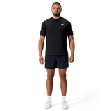 A man faces forward against a white background, wearing the Canterbury Everest Training Tee in black, paired with black shorts and white athletic shoes.