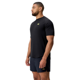 A man stands in side profile, wearing the black Everest Training Tee by Canterbury and dark shorts against a white background—ideal for rugby players who want both style and comfort.