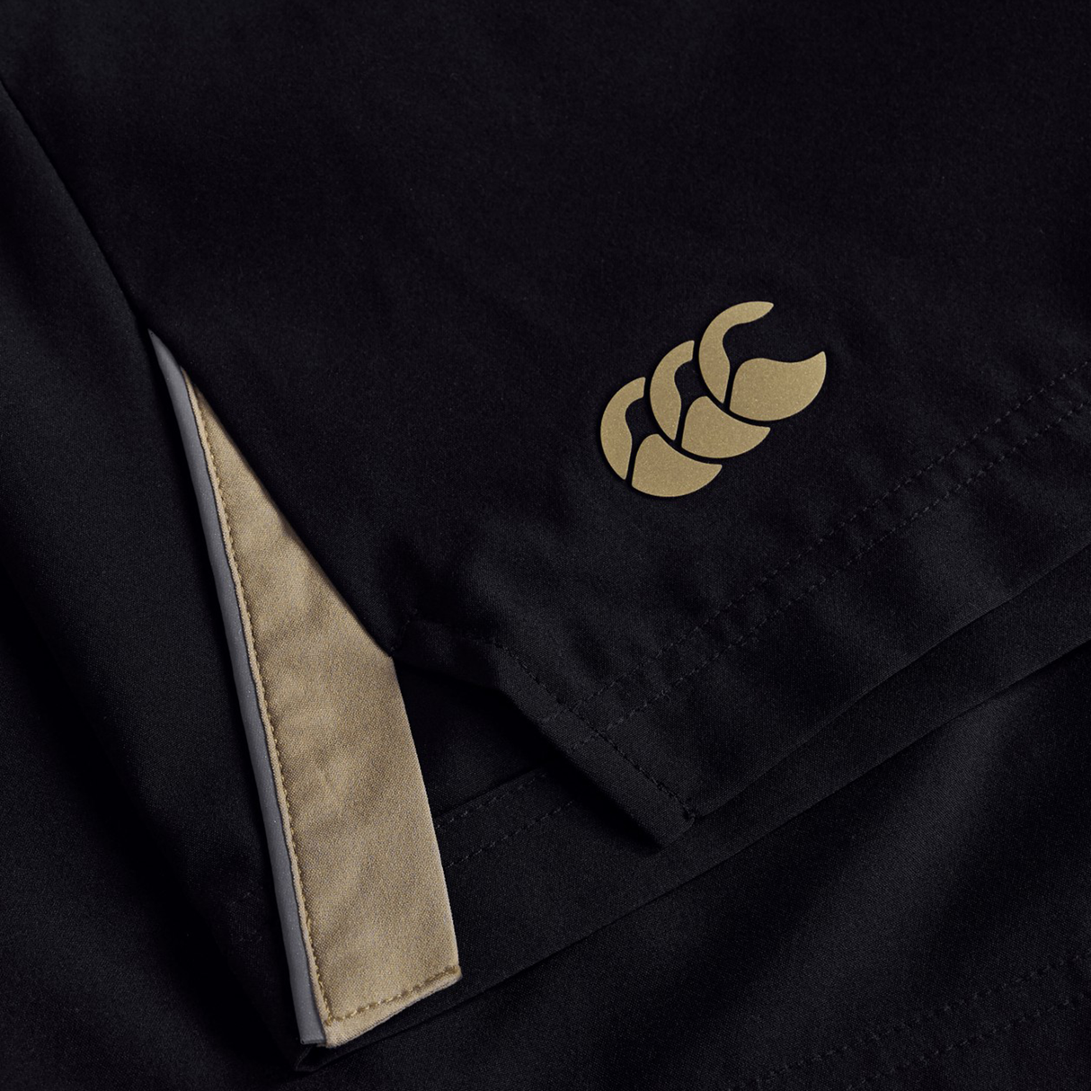 Close-up of Canterbury's Tempo+ 7" Training Short in black, showing a beige logo and a folded corner that reveals the beige inner lining.