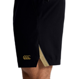 Close-up of a person wearing Canterbury Tempo+ 7" Training Shorts in black, featuring a small gold logo and visible gold inner lining near the hem.