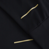 Close-up of black textured fabric from the Canterbury Tempo+ 1/4 Zip Training Top, showing two thin gold-colored lines—one straight, one wavy—across overlapping folds.