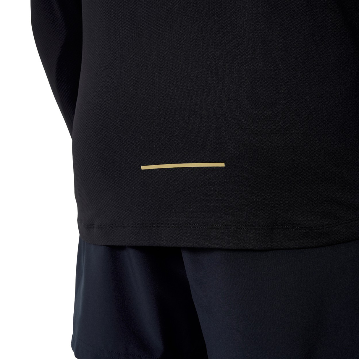 Someone wears a Canterbury Tempo+ 1/4 Zip Training Top in black with a small horizontal beige line near the hem, paired with black shorts. The upper body is mostly out of frame.