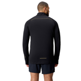 A man, seen from behind, wears the Canterbury Tempo+ 1/4 Zip Training Top in black with yellow accents and black shorts, set against a plain white background.