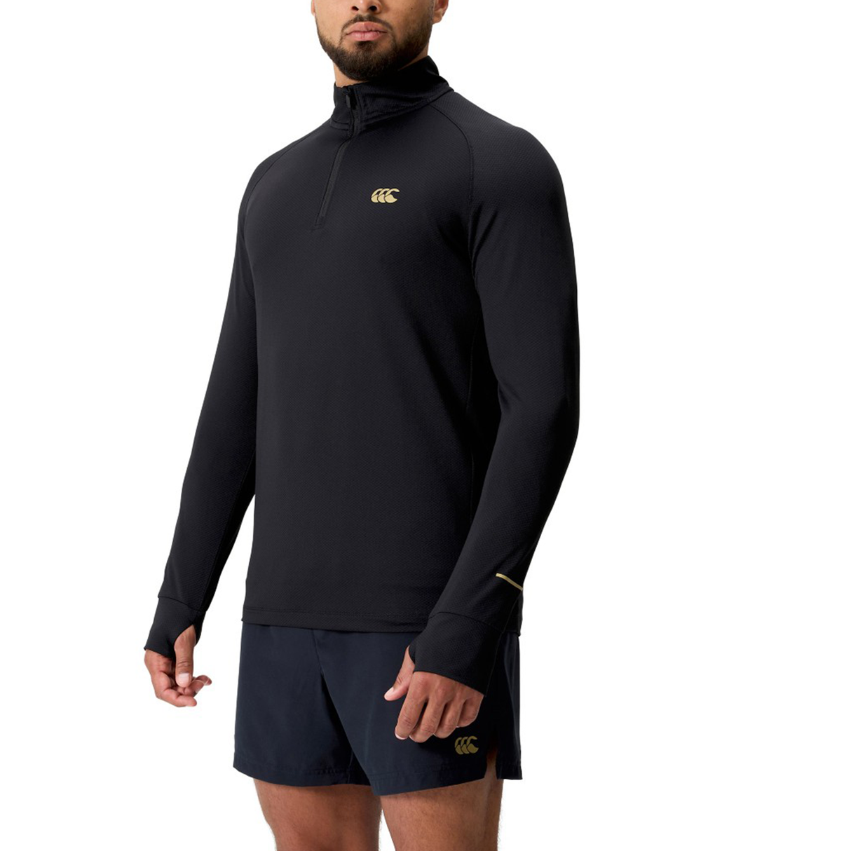 A man in a black Canterbury Tempo+ 1/4 Zip Training Top and matching black shorts, each with a gold logo, ideal for rugby training.