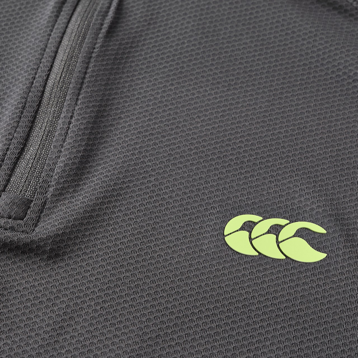 Close-up of the Canterbury Tempo+ 1/4 Zip Training Top, showcasing its textured dark grey fabric, partial zipper, and yellow Canterbury logo.