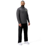 A man faces forward wearing a gray Tempo+ 1/4 Zip Training Top by Canterbury, black pants, and white sneakers against a plain white background.