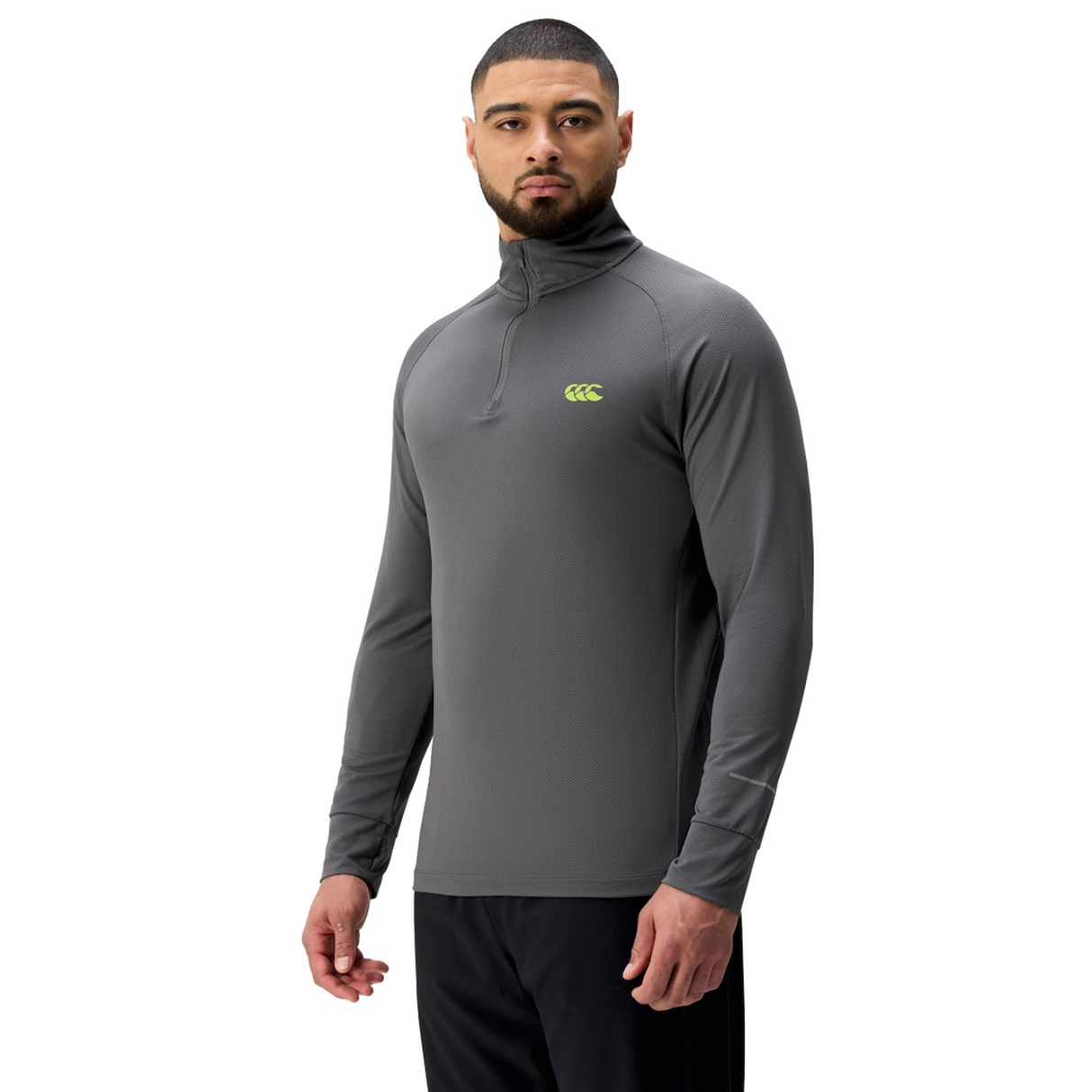 A man stands against a white background wearing a gray Canterbury Tempo+ 1/4 Zip Training Top featuring a neon green logo.