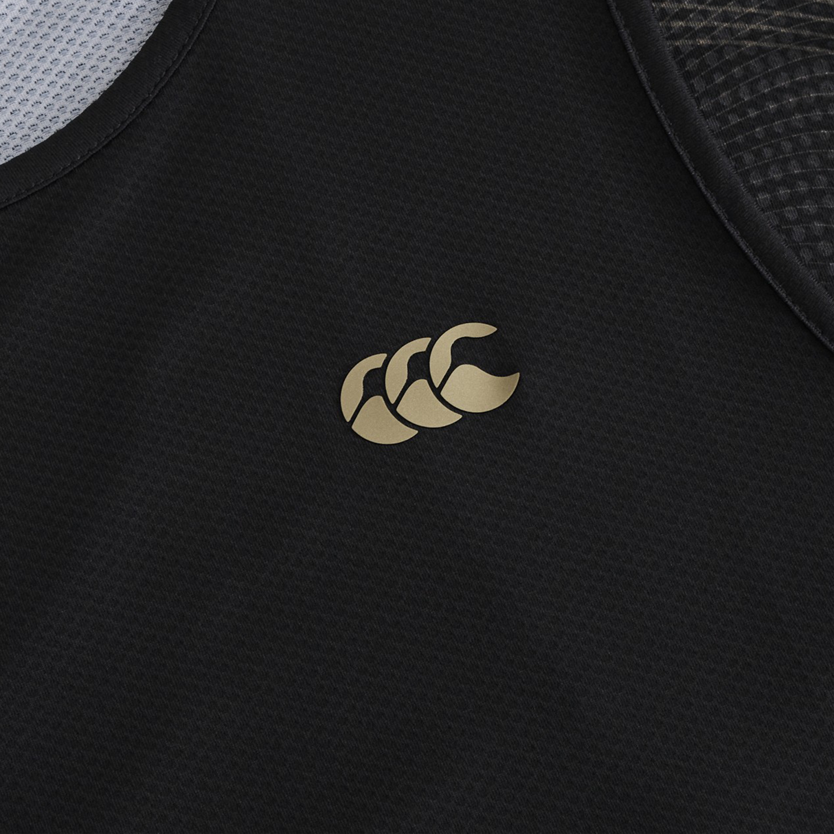 Close-up of the Tempo+ Singlet by Canterbury, a black rugby training top with a gold Canterbury logo on textured, moisture-wicking fabric for breathable performance.