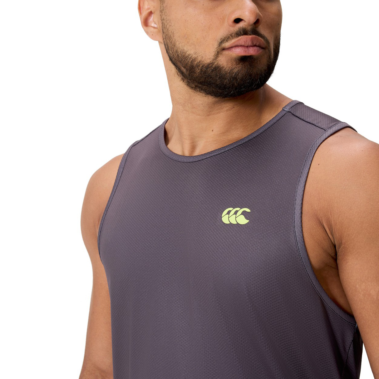 A man wearing the Canterbury Tempo+ Singlet, a sleeveless purple performance top with a yellow Canterbury logo on the chest, stands against a white background.