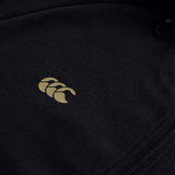 Close-up of the Canterbury Tempo+ Full-Zip Hoodie by Canterbury, a black lightweight stretch hoodie featuring a small gold logo with three overlapping shapes and a visible right-side zipper.