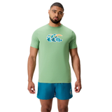 A man wearing a light green Canterbury Uglies CCC Logo T-Shirt by Canterbury H225 and teal athletic shorts stands facing forward against a plain white background.